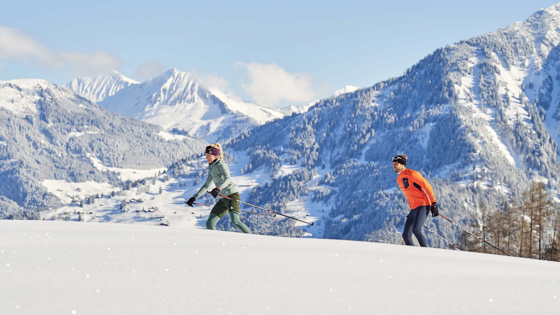 Zwei Personen beim Langlaufen im schneebedeckten Gebirge an einem sonnigen Tag